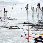 Image of many ski poles at the bottom of a ski hill