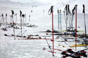 Image of many ski poles at the bottom of a ski hill