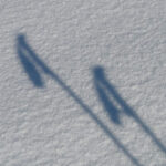 Image of the shadow of ski poles in the snow, representing wondering when someone should replace their ski poles.