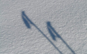 Image of the shadow of ski poles in the snow, representing wondering when someone should replace their ski poles.